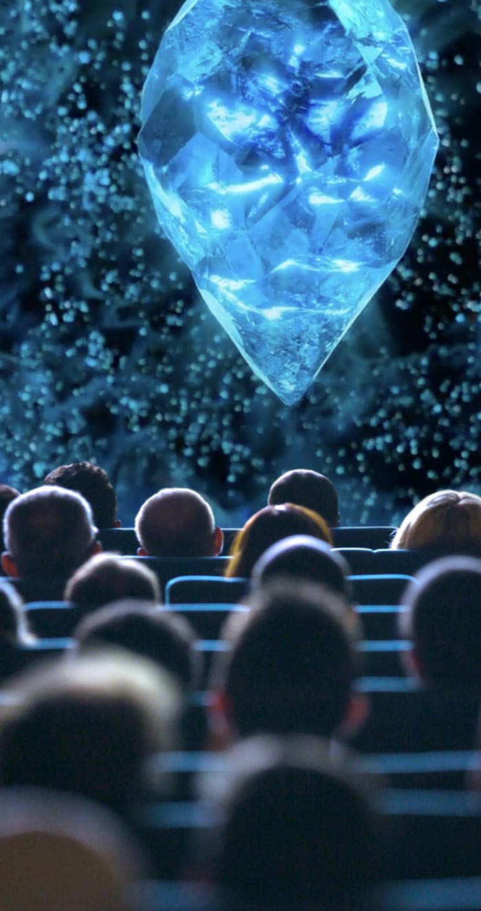 People in a movie theatre viewing a crystal on the screen.